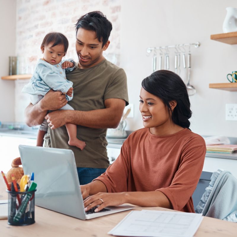 Internet,,Family,And,Parents,Doing,Research,On,Down,Syndrome,With Internet, family and parents doing research on down syndrome with baby on a laptop in their house. Mother and father with smile for child and working on taxes or finance budget on the computer